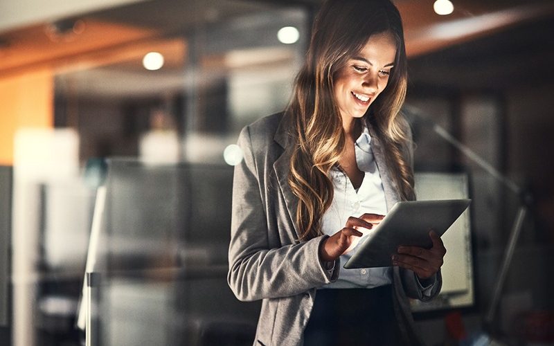 Cropped shot of a young attractive businesswoman using a tablet while working late at night in the office
